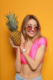 Photo of Young woman with fresh pineapple on yellow background. Exotic fruit