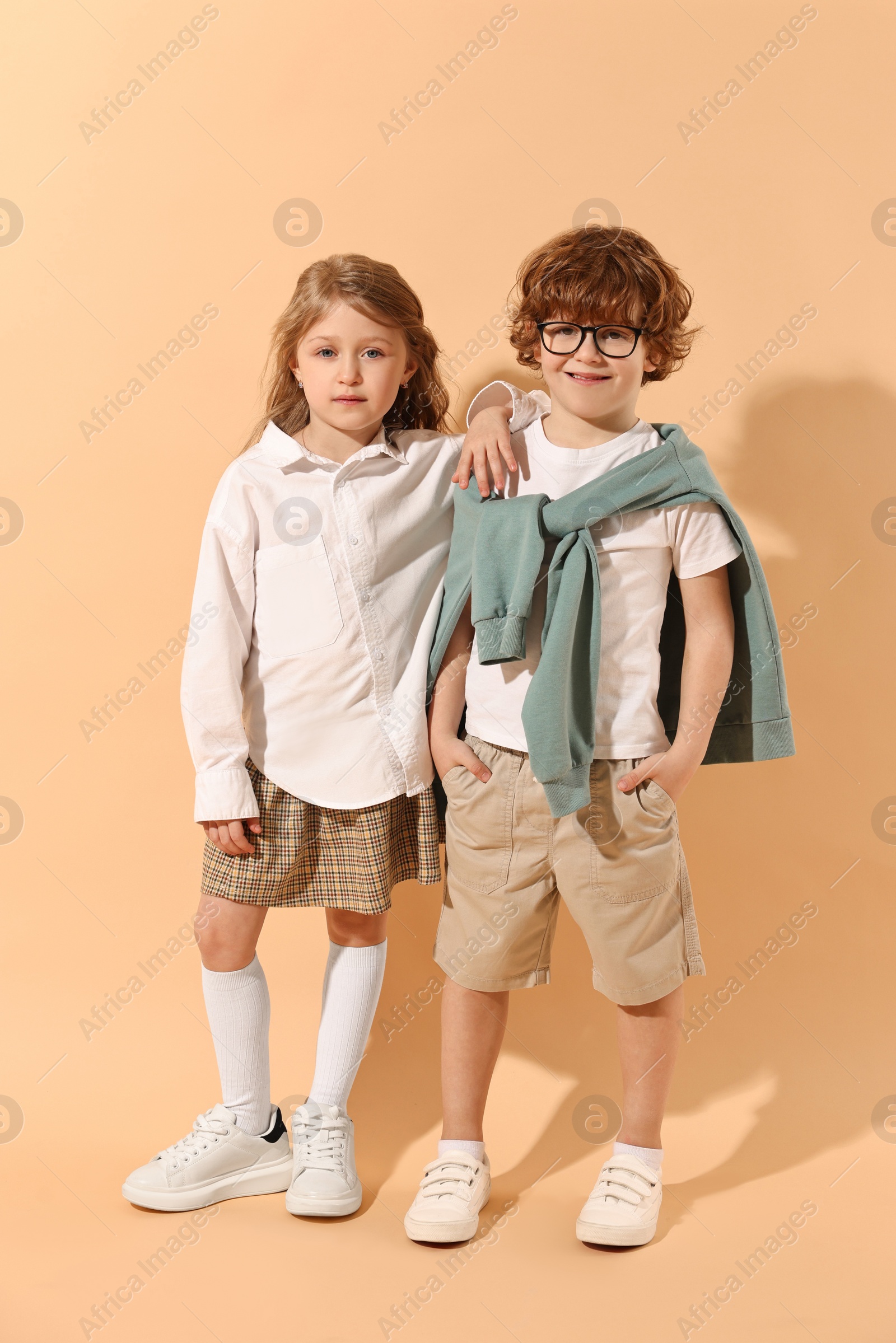 Photo of Fashion concept. Stylish children on pale orange background