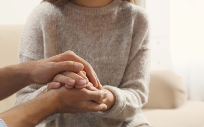 Man comforting woman on light background, closeup of hands. Help and support concept