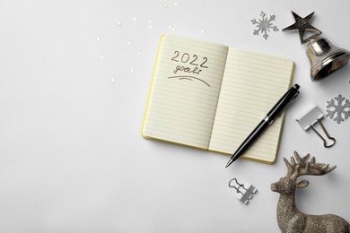Photo of Inscription 2022 Goals written in planner and Christmas decor on white background, flat lay with space for text. New Year aims