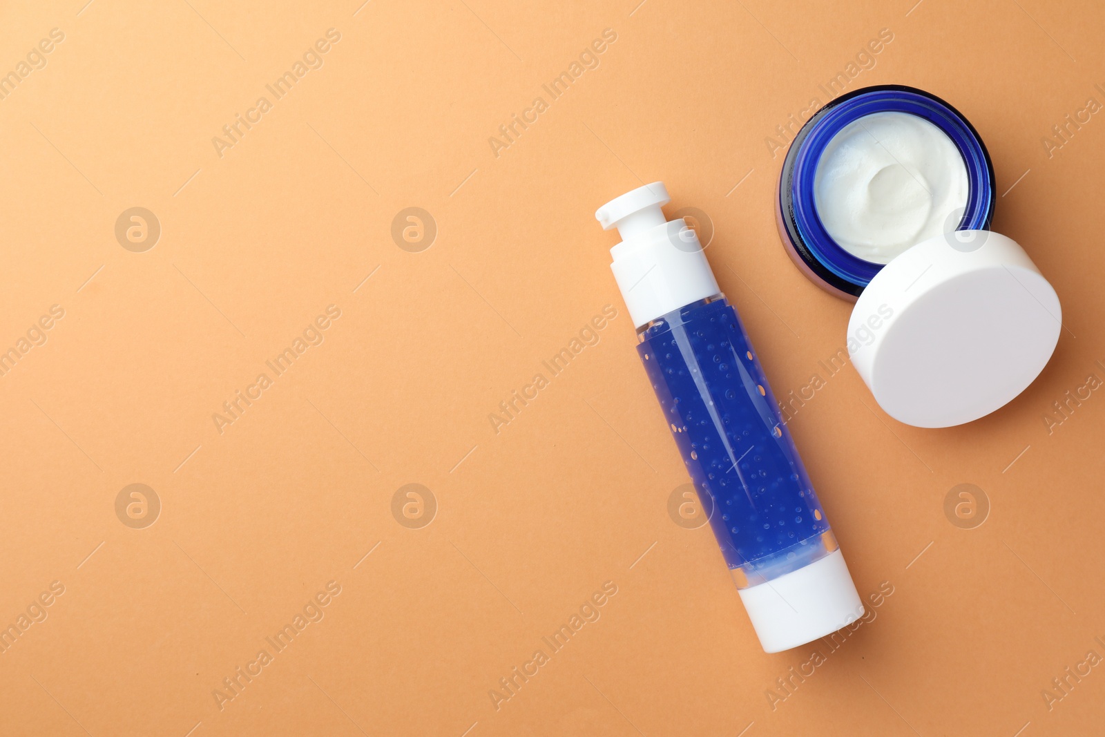 Photo of Bottle and jar of cosmetic products on orange background, flat lay. Space for text