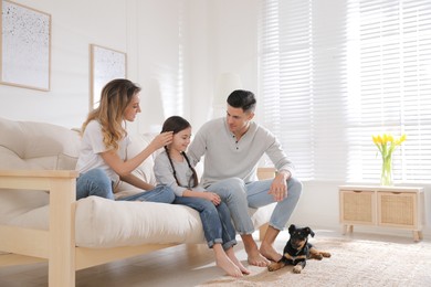 Photo of Happy family on sofa and little puppy in living room