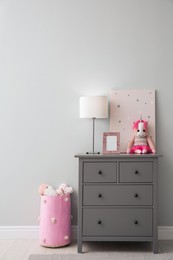 Photo of Modern grey chest of drawers near light wall in child room. Interior design