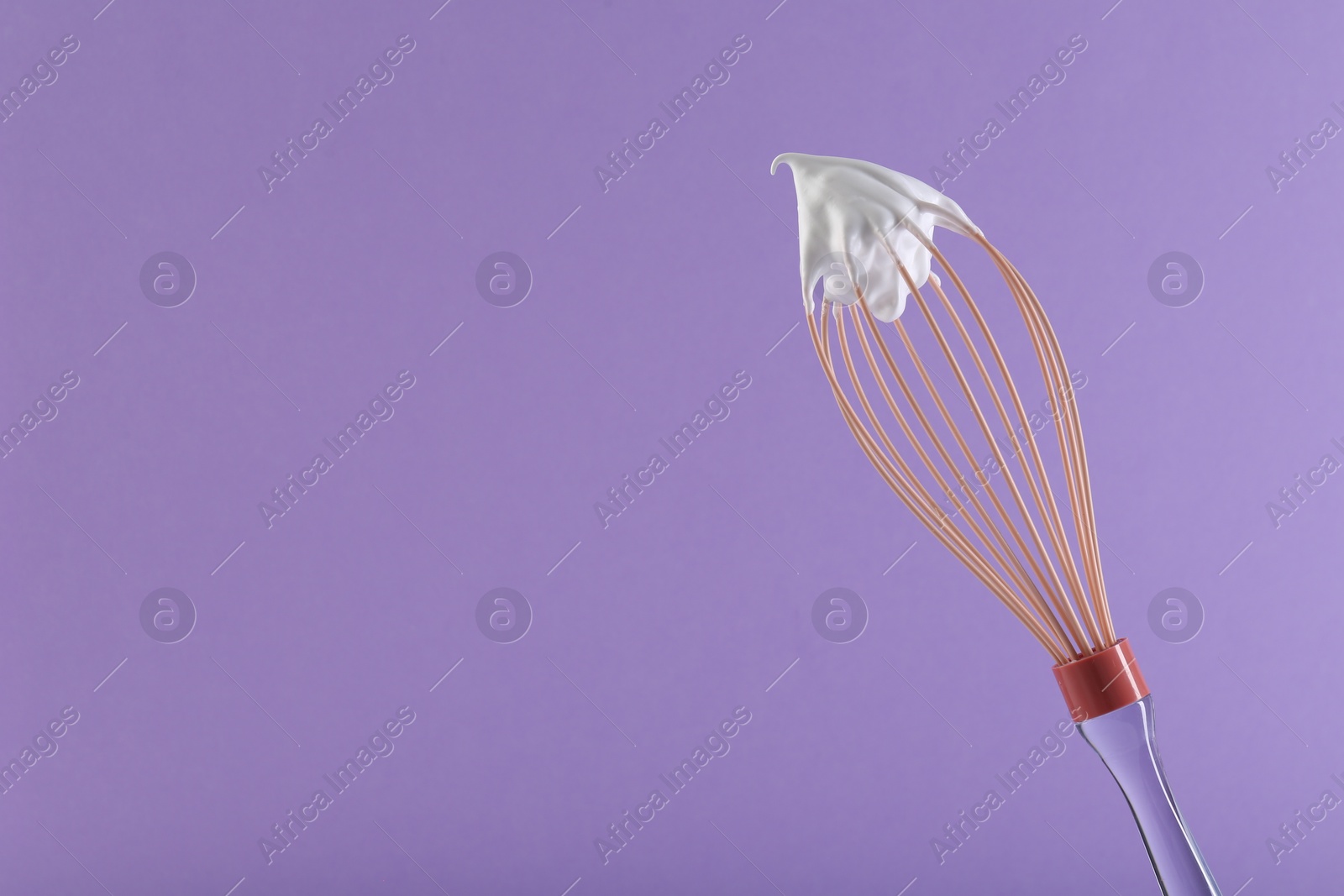 Photo of Whisk with whipped cream on violet background. Space for text