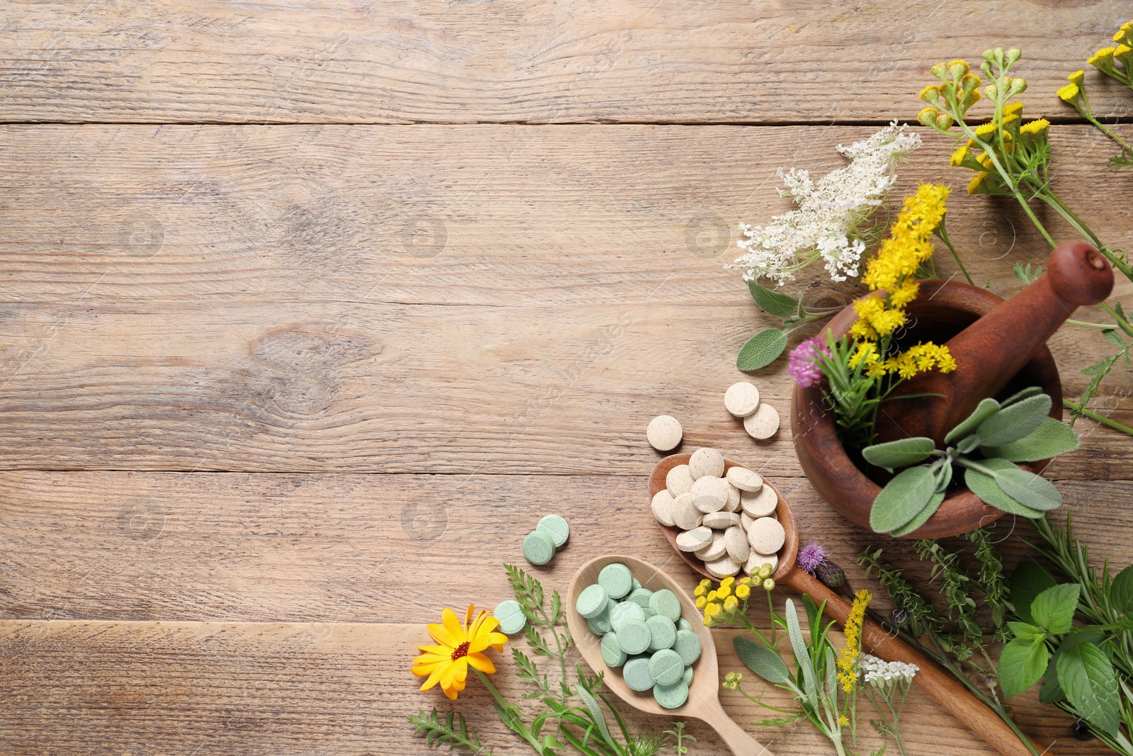 Photo of Different pills, herbs and flowers on wooden table, flat lay with space for text. Dietary supplements