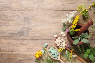 Photo of Different pills, herbs and flowers on wooden table, flat lay with space for text. Dietary supplements