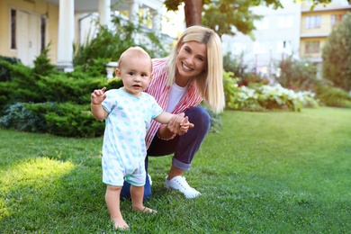 Photo of Nanny with cute little baby on green grass outdoors