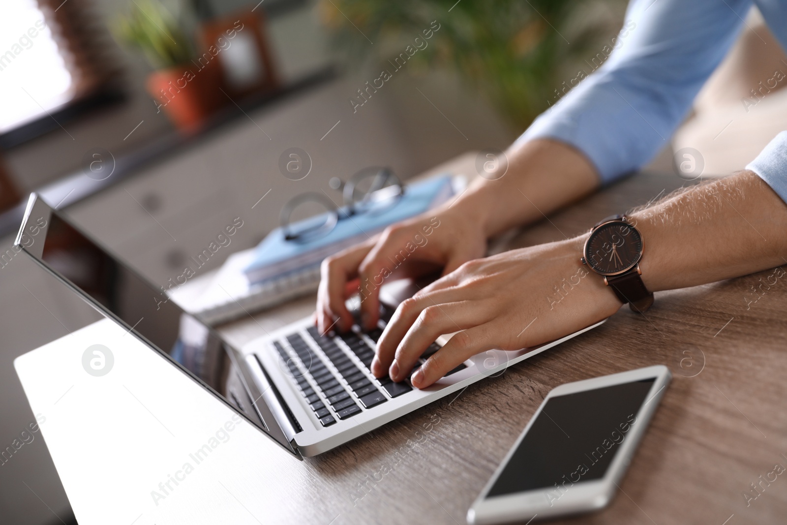 Photo of Man using laptop at table indoors, closeup