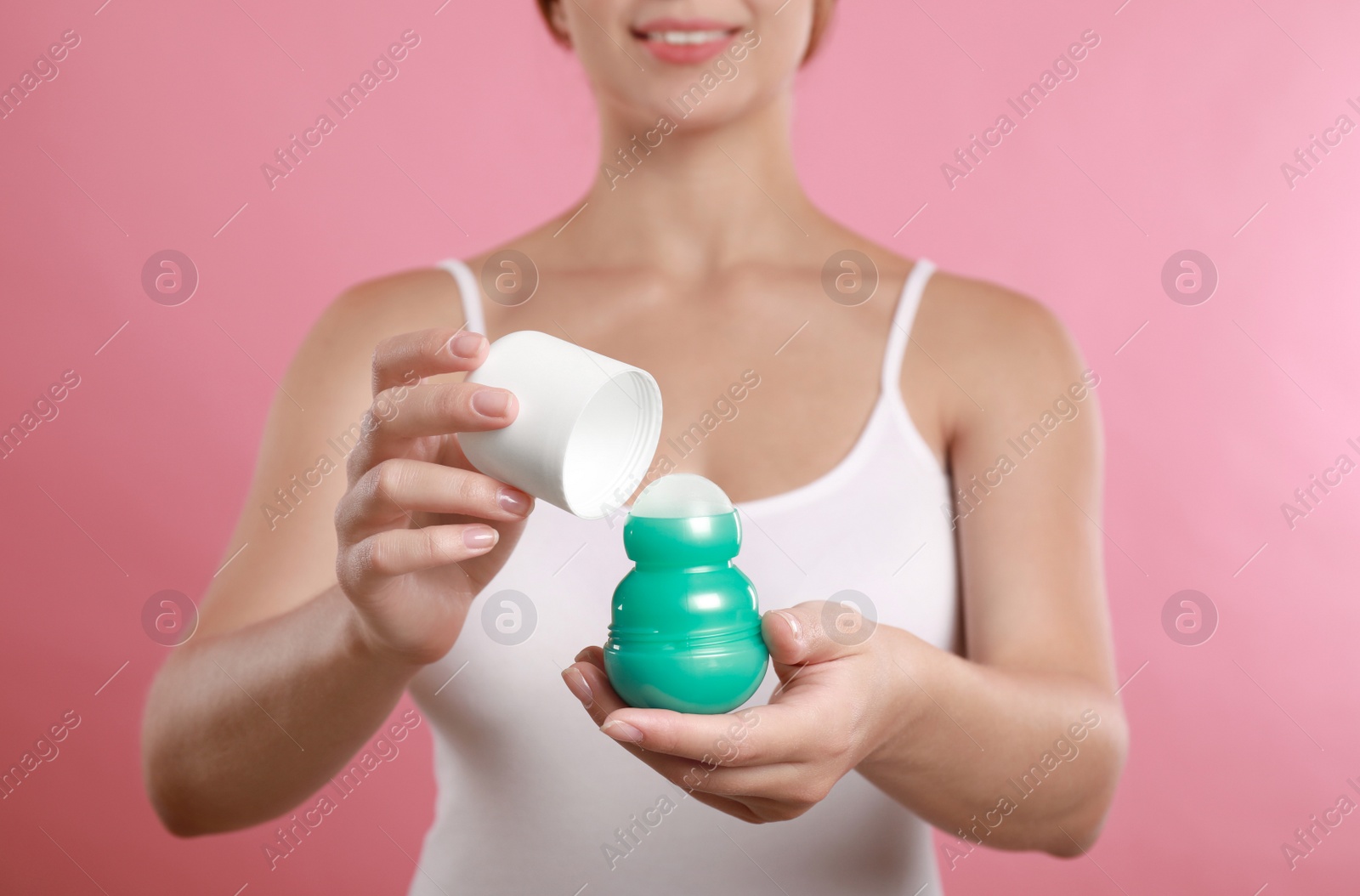 Photo of Young woman holding deodorant on pink background, closeup