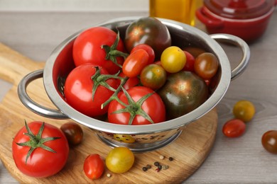 Photo of Metal colander with fresh tomatoes on wooden table, closeup