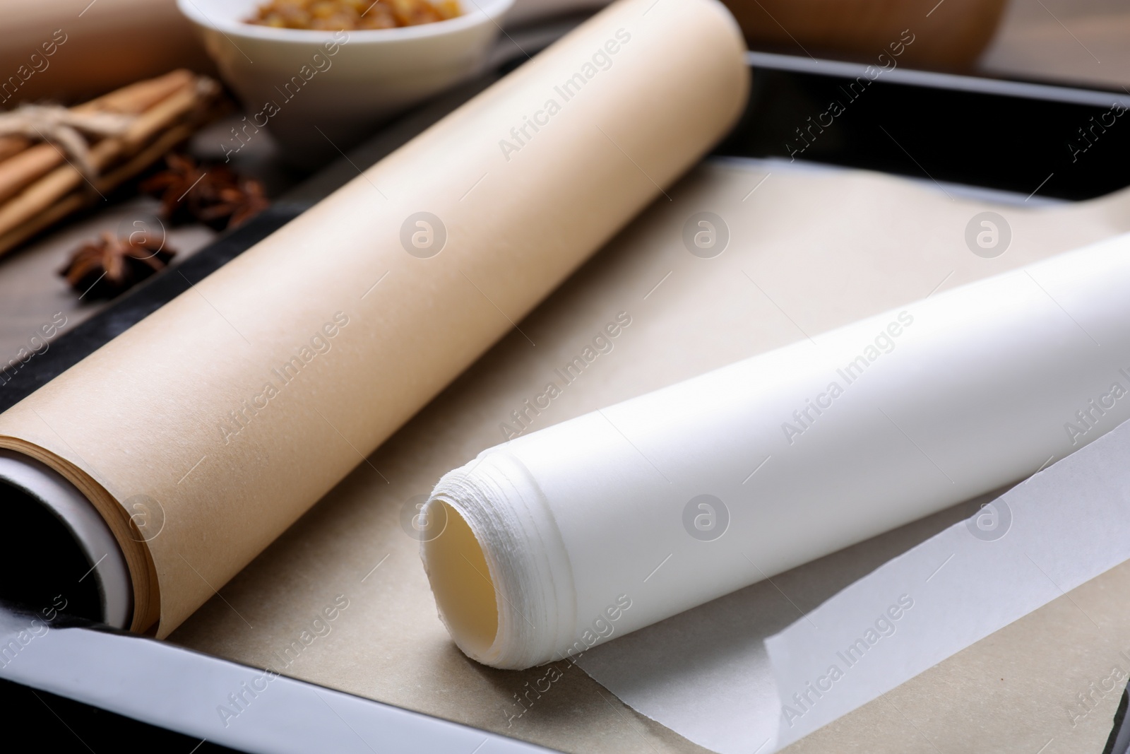 Photo of Rolls of parchment paper in baking pan on table, closeup