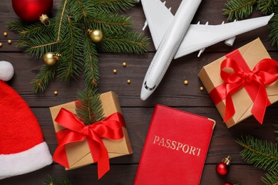 Photo of Flat lay composition with Christmas decorations and toy airplane on wooden background. Winter vacation