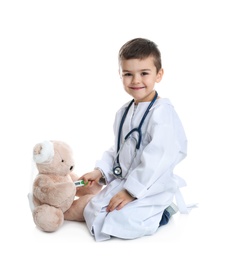 Cute child playing doctor with stuffed toy on white background