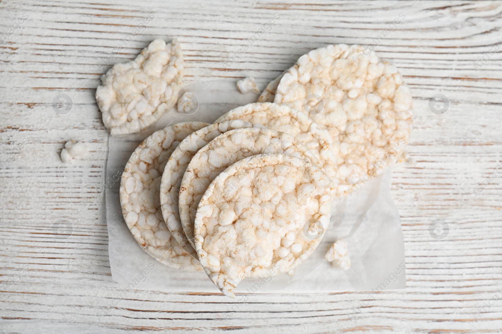 Photo of Puffed rice cakes on white wooden table, flat lay