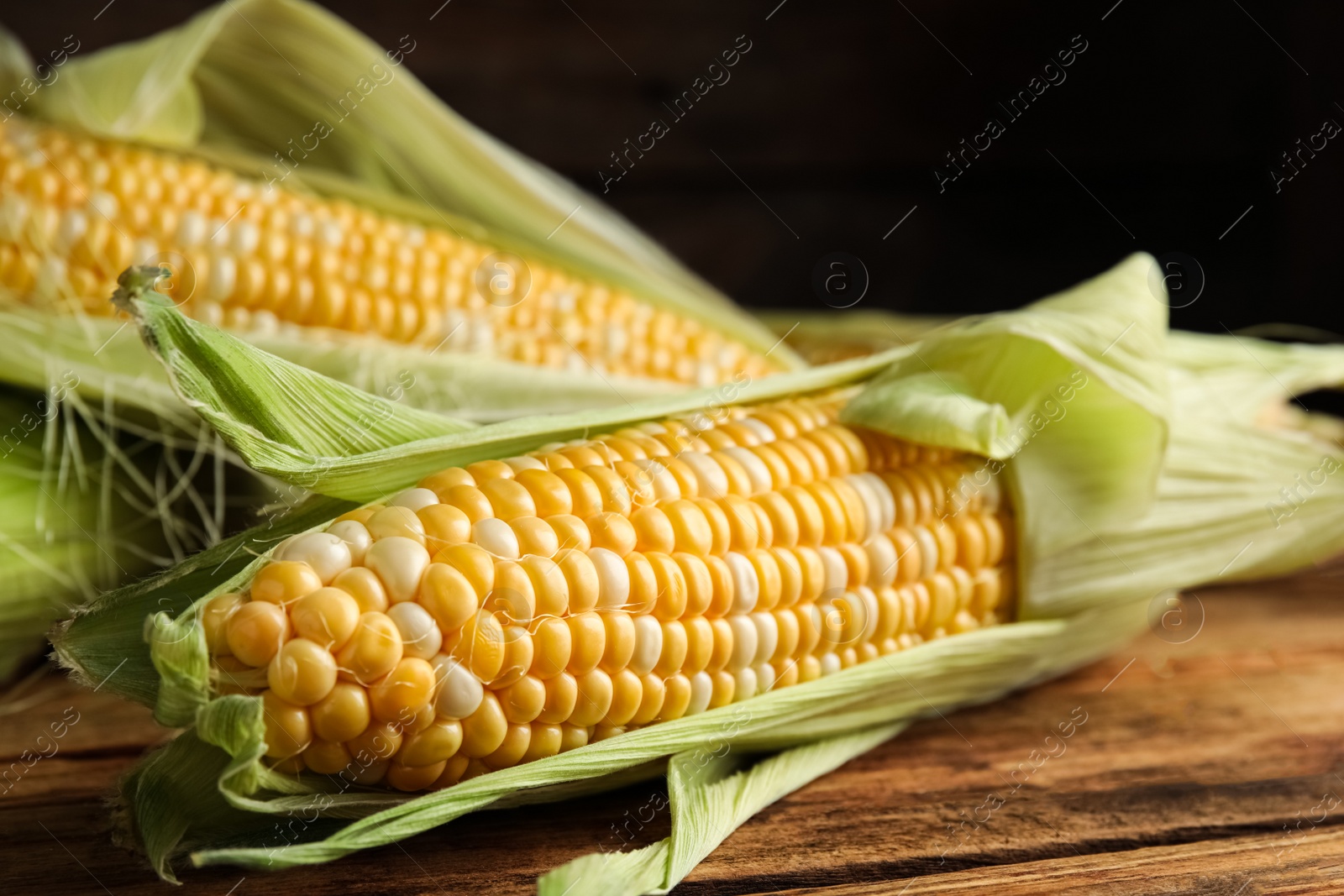 Photo of Tasty sweet corn cobs on wooden table, closeup