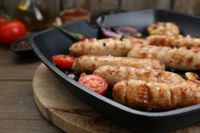 Photo of Tasty grilled sausages with vegetables on wooden table, closeup. Space for text