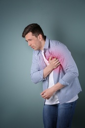 Photo of Young man having heart attack on color background