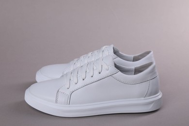 Photo of Pair of stylish white sneakers on grey background