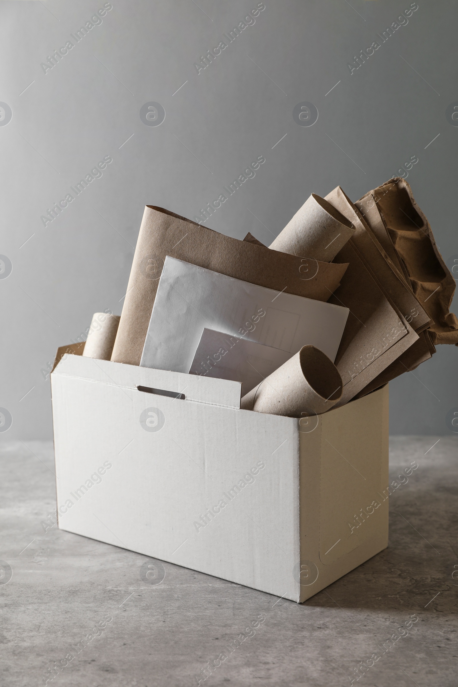 Photo of Box with different waste paper on grey table