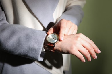 Woman with luxury wristwatch on dark green background, closeup