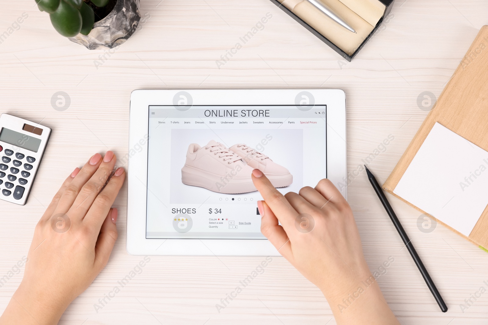 Photo of Woman with tablet shopping online at white wooden table, top view