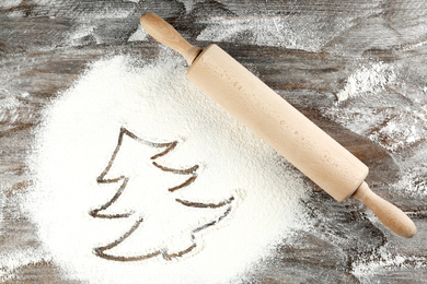 Christmas tree made of flour near rolling pin on wooden table, top view