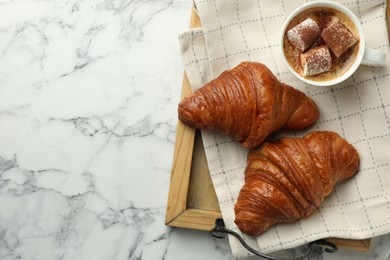 Photo of Tasty croissants served with cup of hot drink on white marble table, top view. Space for text