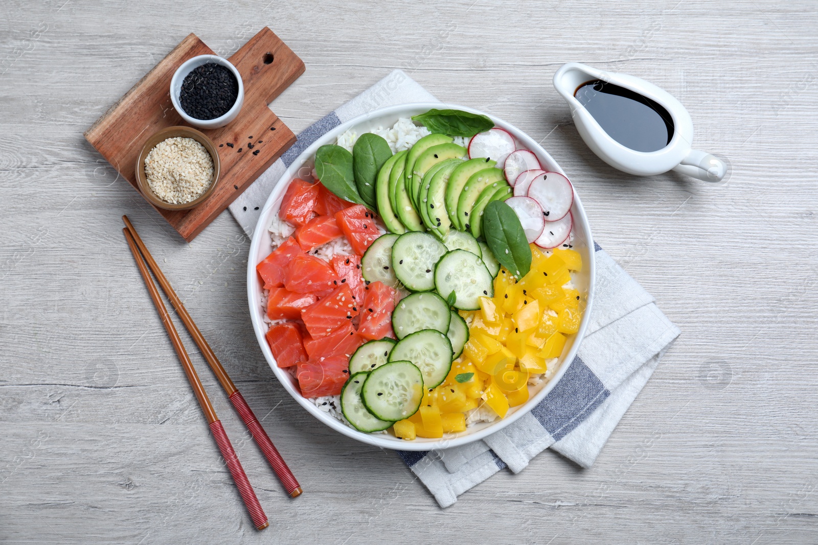 Photo of Delicious poke bowl with salmon and vegetables served on wooden table, flat lay