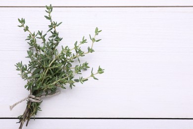 Photo of Bunch of fresh thyme on white wooden table, top view. Space for text