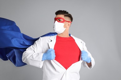 Doctor wearing face mask and cape on grey background. Super hero power for medicine