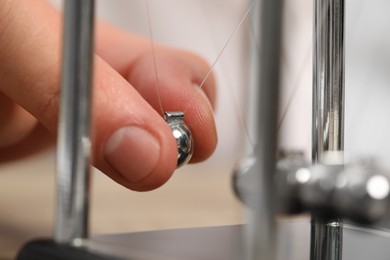 Man playing with Newton's cradle, closeup. Physics law of energy conservation
