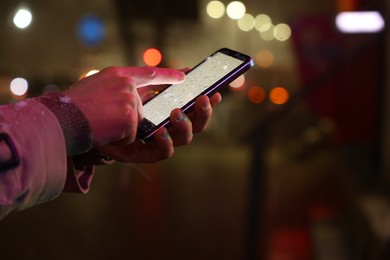Man using smartphone on night city street, closeup. Space for text