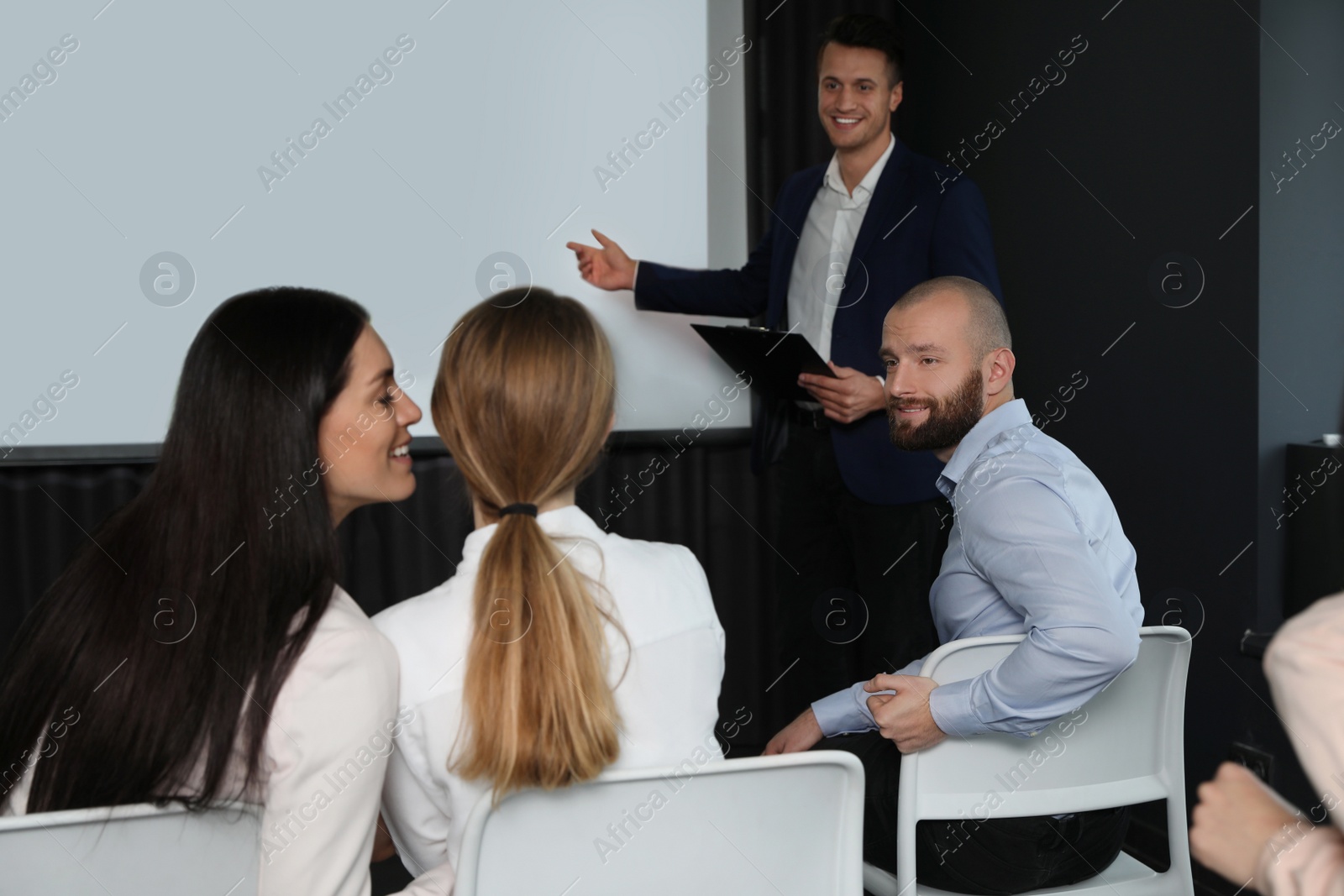 Photo of Business people at seminar in conference room with video projection screen