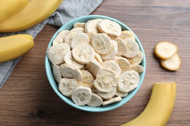 Photo of Freeze dried and fresh bananas on wooden table, flat lay