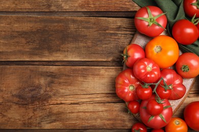 Photo of Many different ripe tomatoes on wooden table, flat lay. Space for text