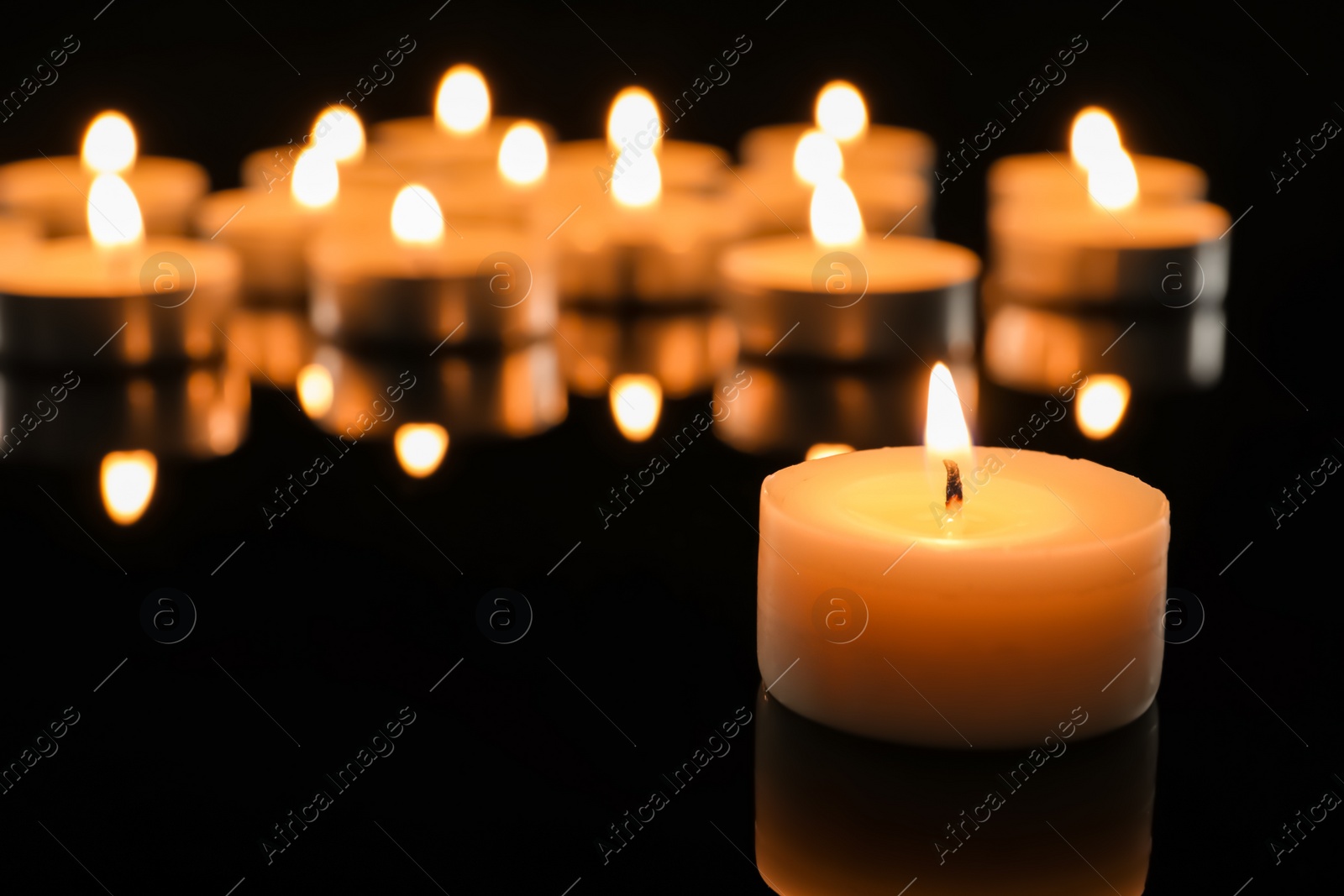 Photo of Wax candle burning on table in darkness, closeup