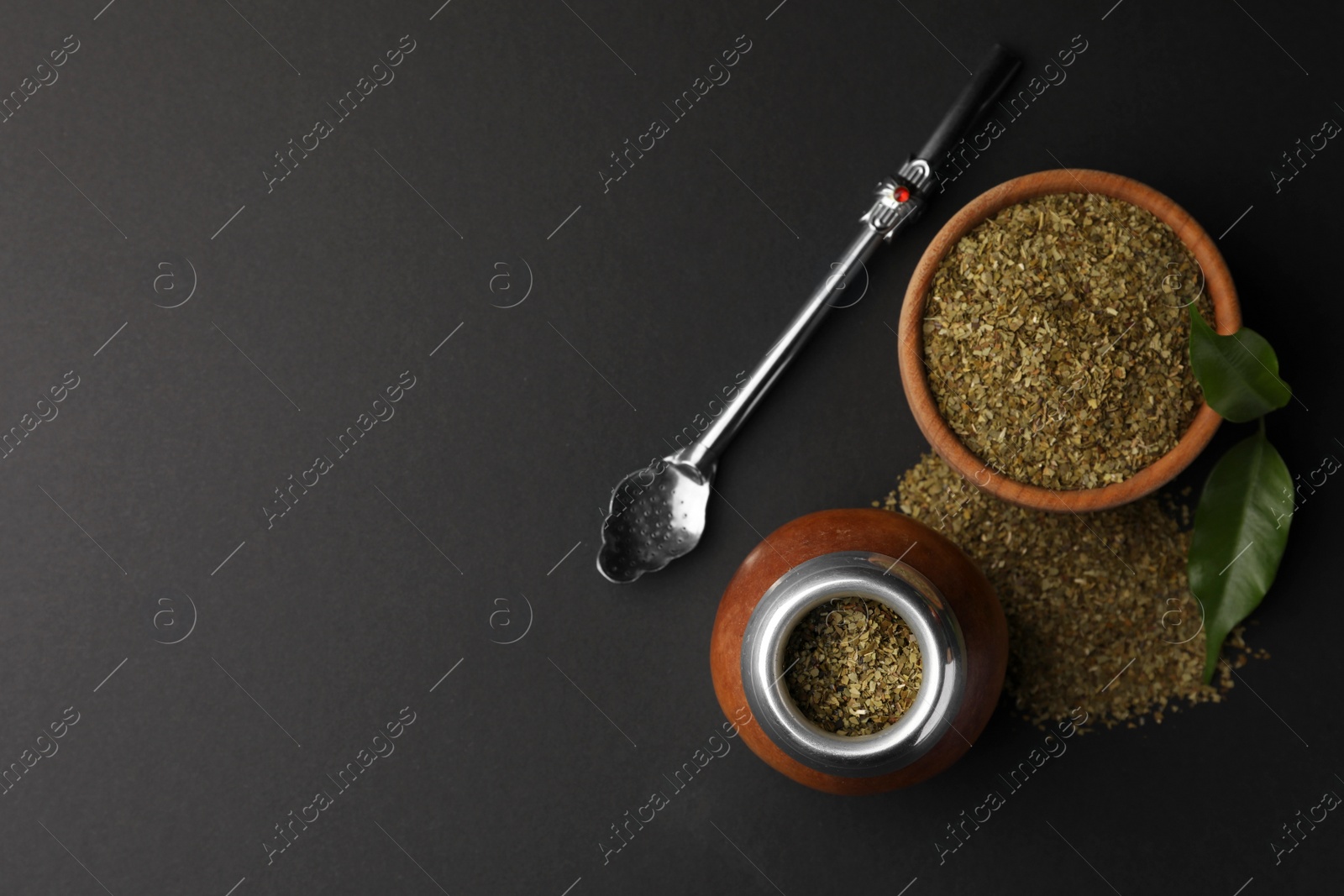 Photo of Calabash with mate tea and bombilla on black table, flat lay. Space for text