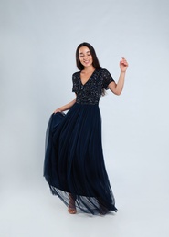 Young woman wearing stylish dress on light grey background