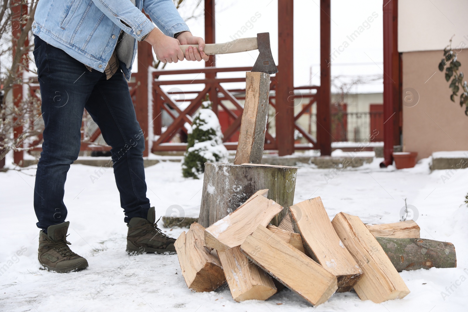 Photo of Man chopping wood with axe outdoors on winter day, closeup