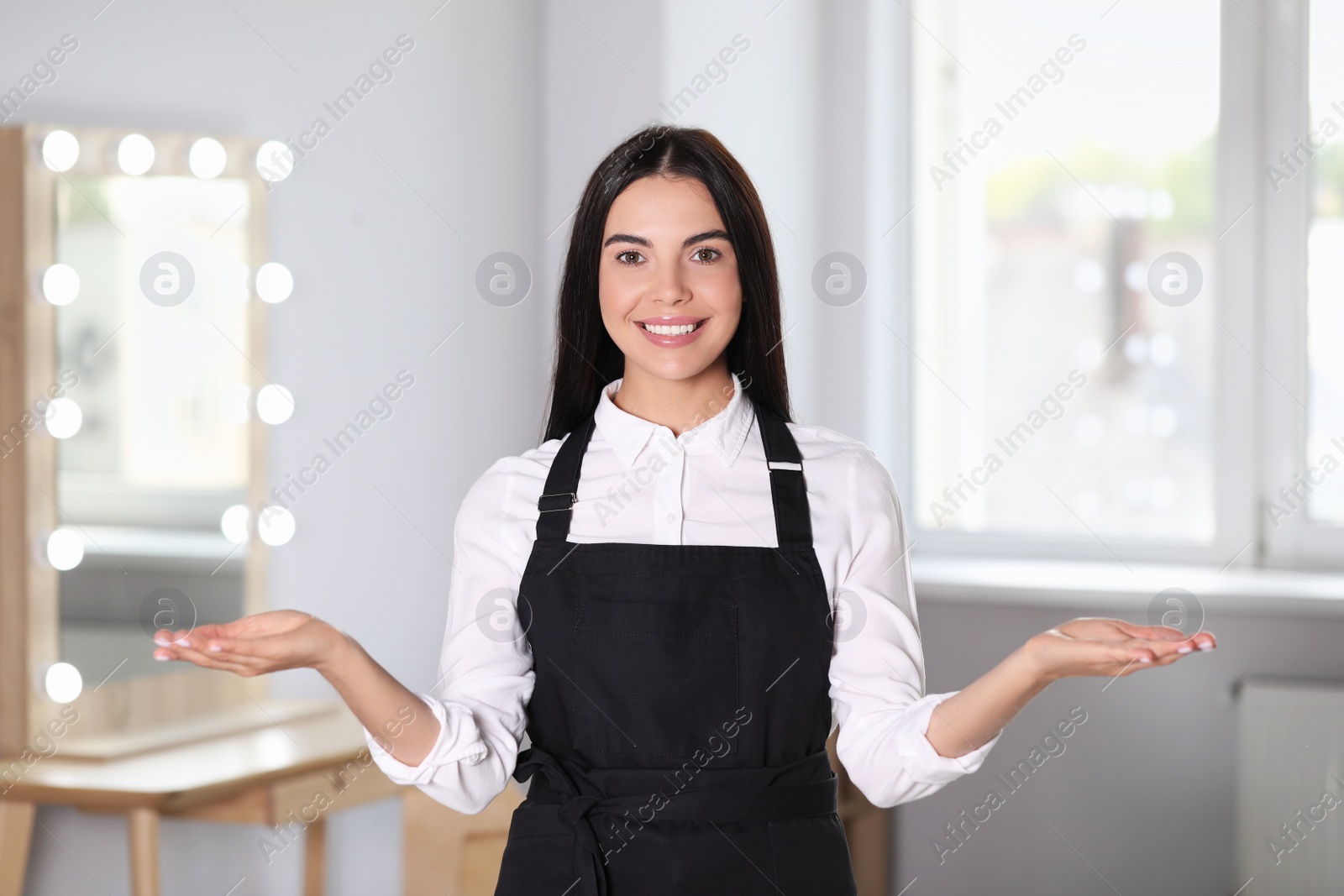 Photo of Portrait of professional hairdresser wearing black apron in beauty salon