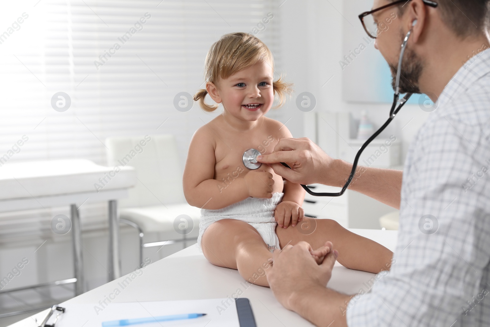 Photo of Pediatrician examining baby with stethoscope in clinic