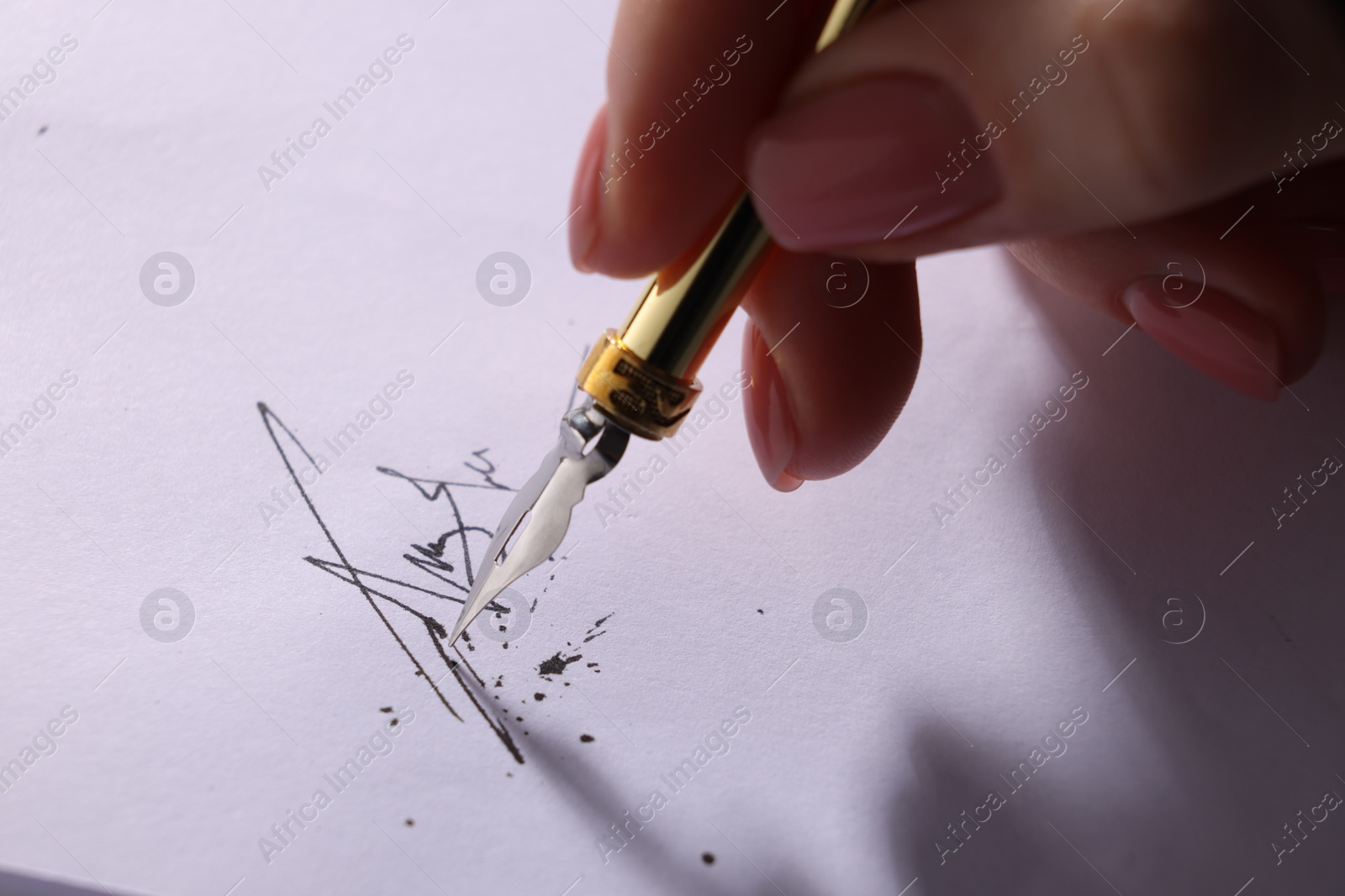 Photo of Woman signing on sheet of paper with fountain pen, closeup