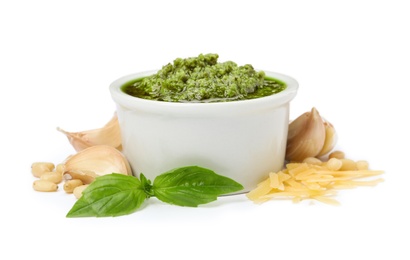 Composition with bowl of tasty pesto sauce isolated on white