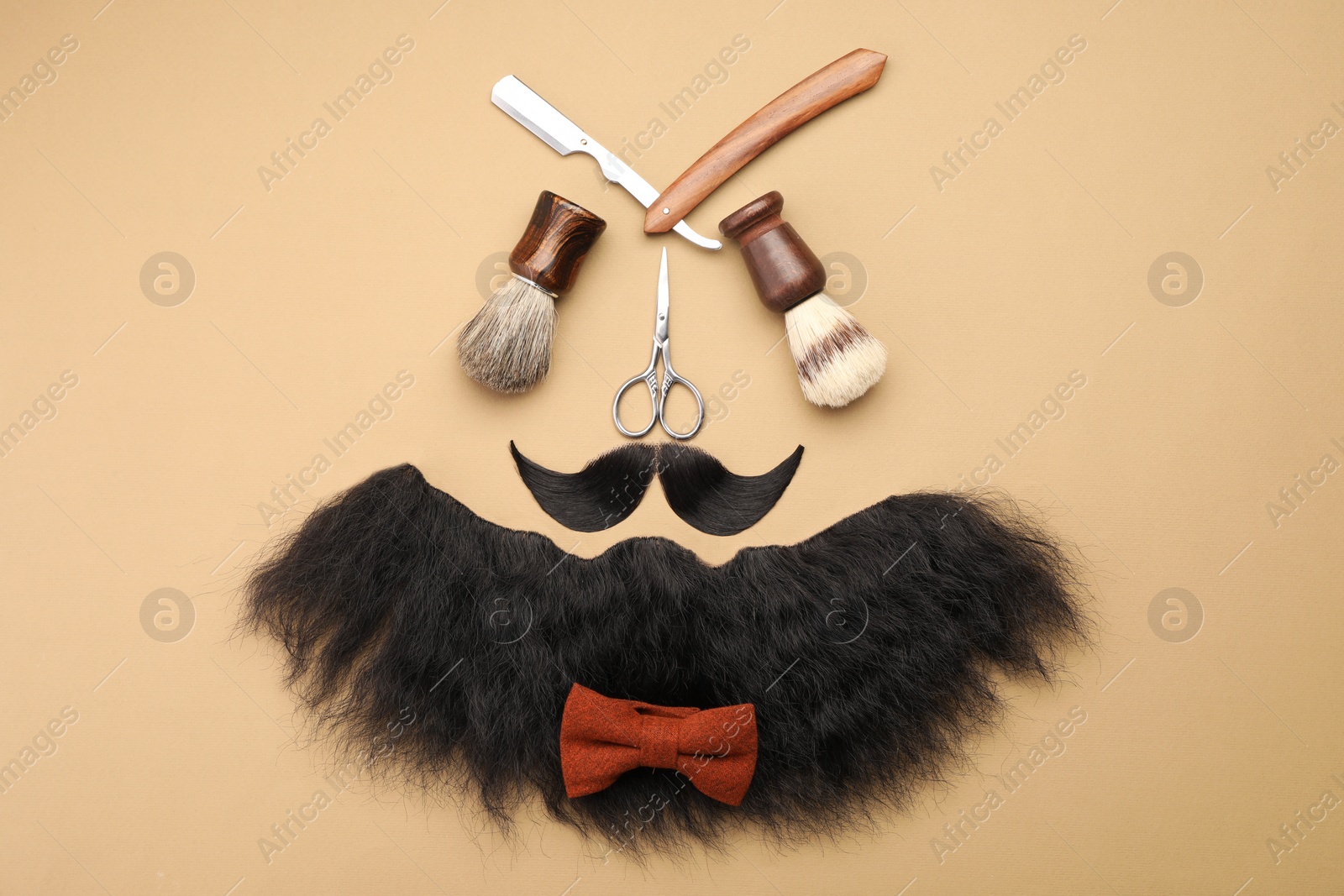 Photo of Artificial moustache, beard and barber tools on beige background, flat lay