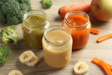 Photo of Tasty baby food in jars and ingredients on wooden table