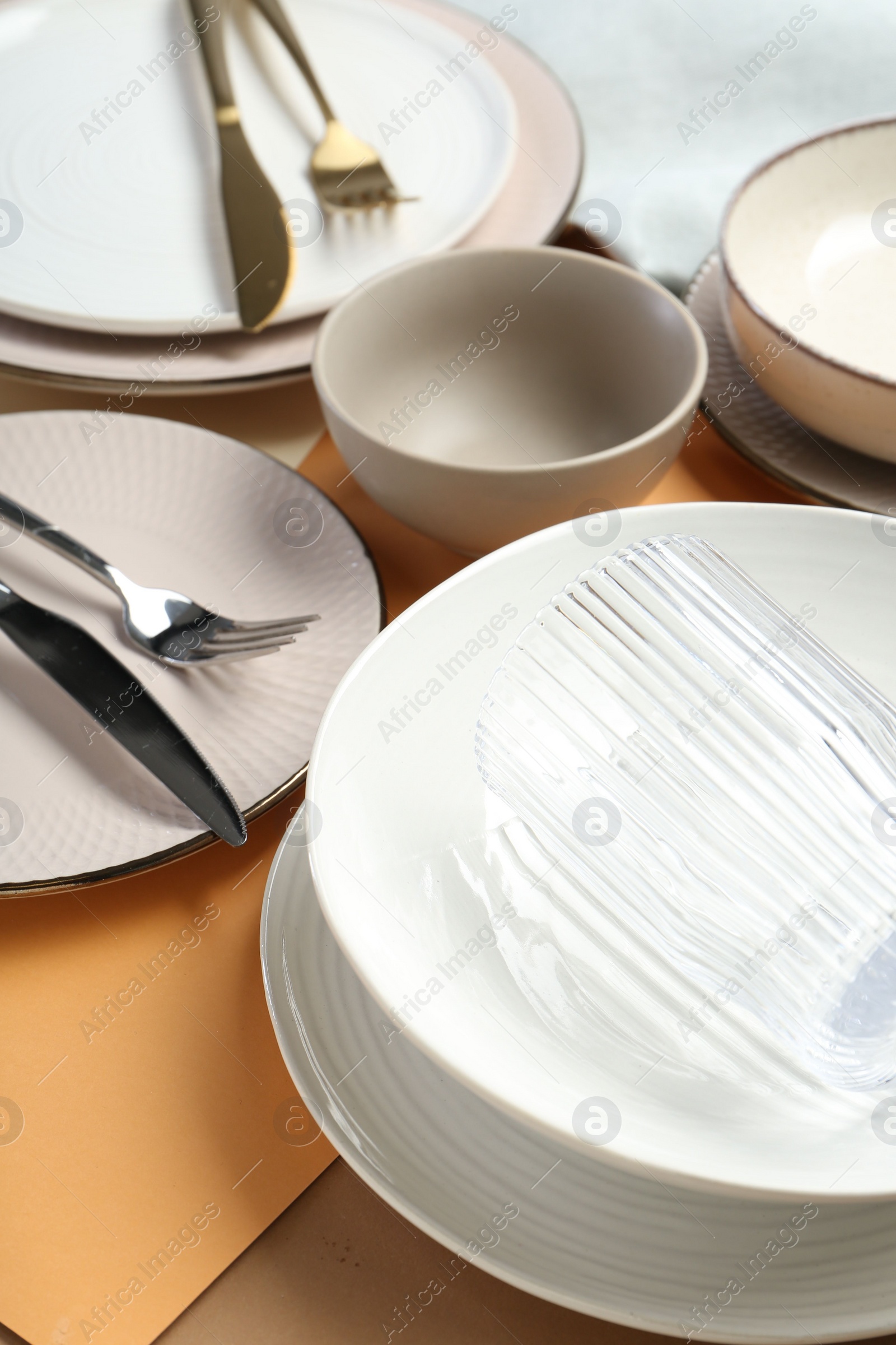 Photo of Clean plates, bowls, glass and cutlery on table