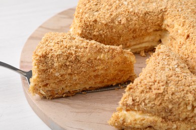 Taking piece of delicious Napoleon cake from table, closeup