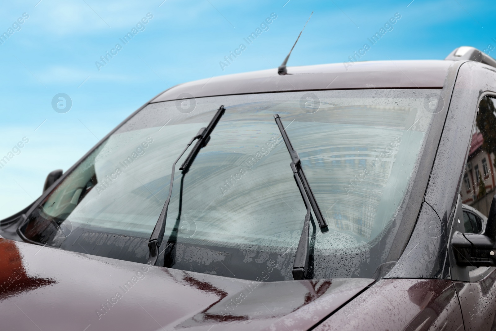 Photo of Car wipers cleaning water drops from windshield glass outdoors, closeup