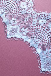 Photo of White lace on purple background, top view. Space for text