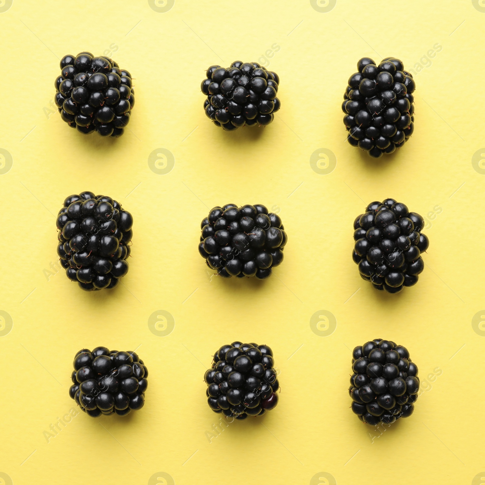 Photo of Tasty ripe blackberries on yellow background, flat lay